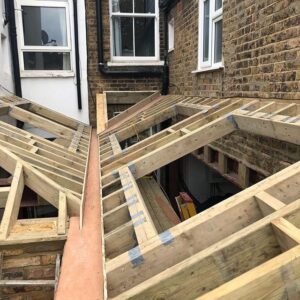 Houten dakconstructie in aanbouw tussen bestaande bakstenen gevels