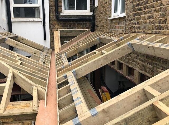 Houten dakconstructie in aanbouw tussen bestaande bakstenen gevels